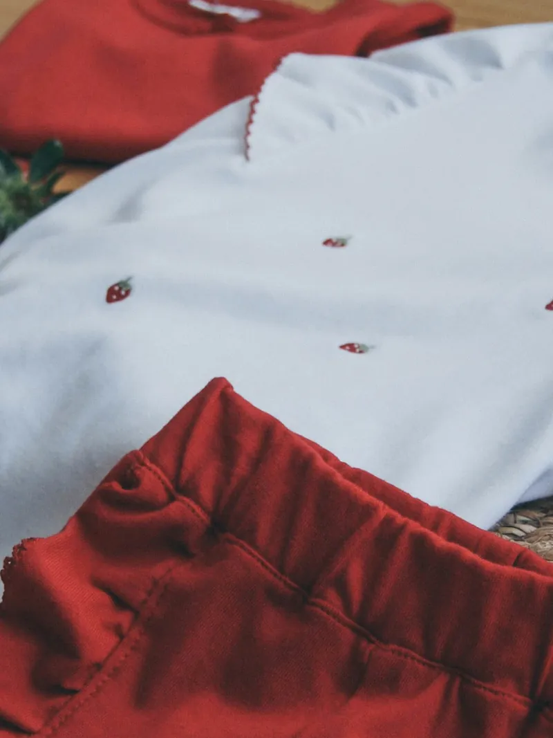 White embroidered tee and red shorts set laid flat